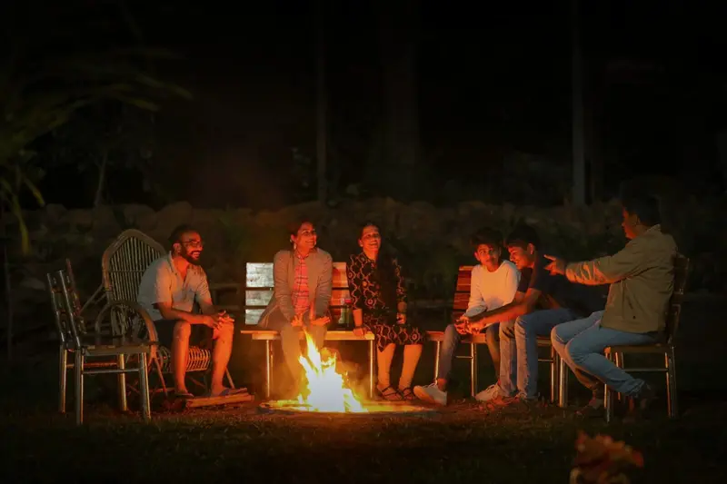 Guests sitting around a night bonfire